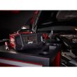 redresor auto roșu plasat pe un stand lângă o mașină cu capota deschisă